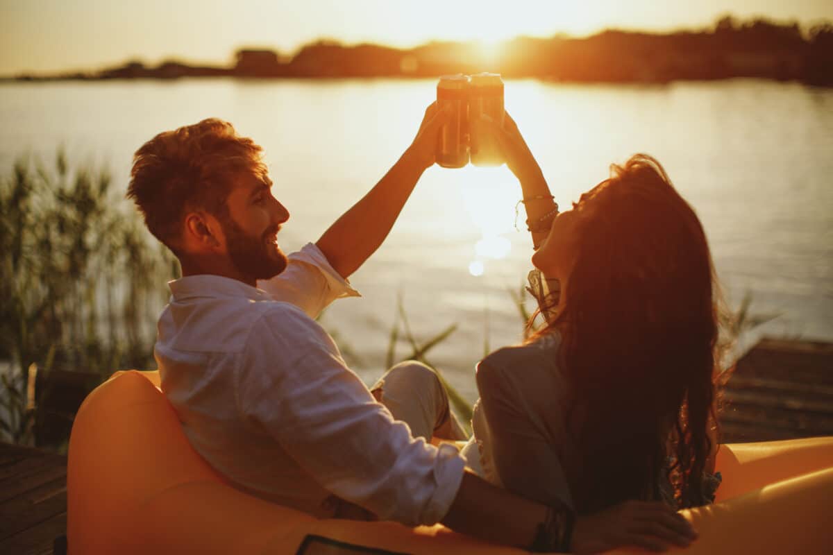 Couple drinking canned beverage at sunset