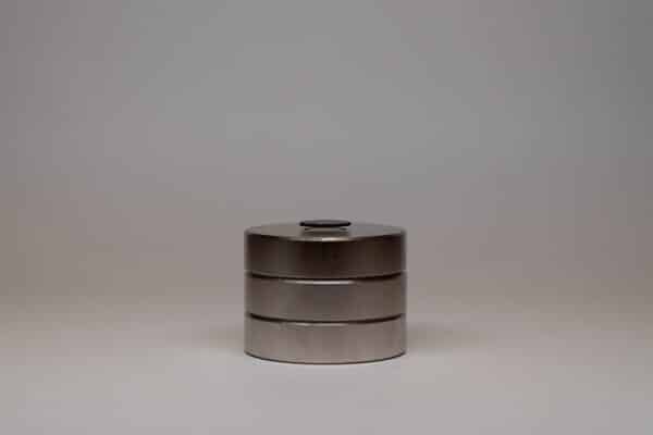 A photograph of a black graphite disk floating above a stack of three, round magnets