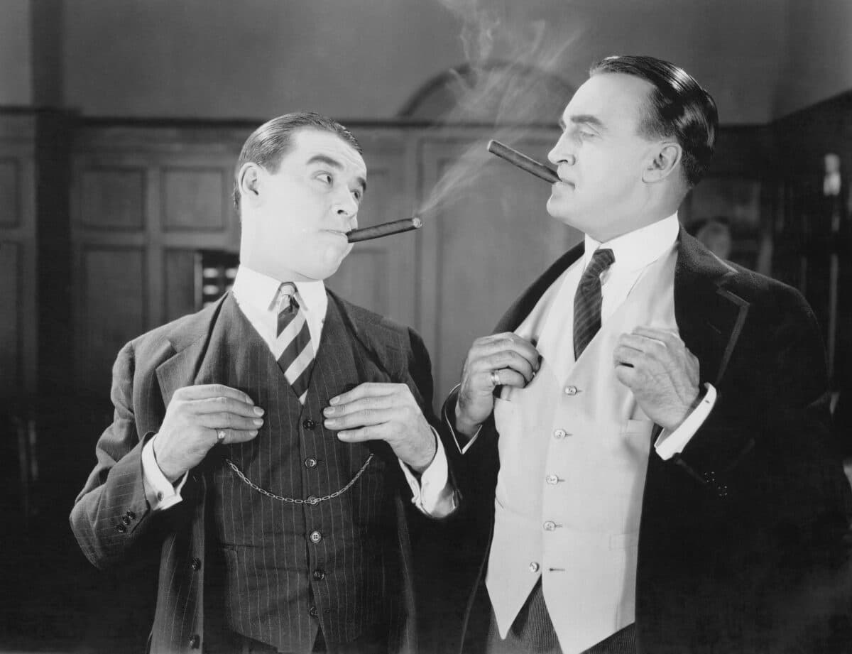 Rich men smoking cigars in vintage movie or TV scene