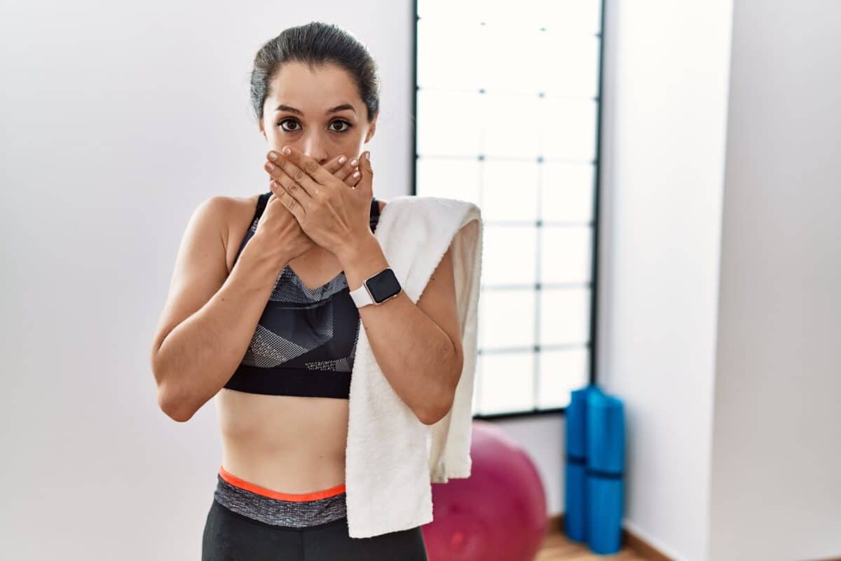 Woman feeling like she might vomit covering her mouth while working out