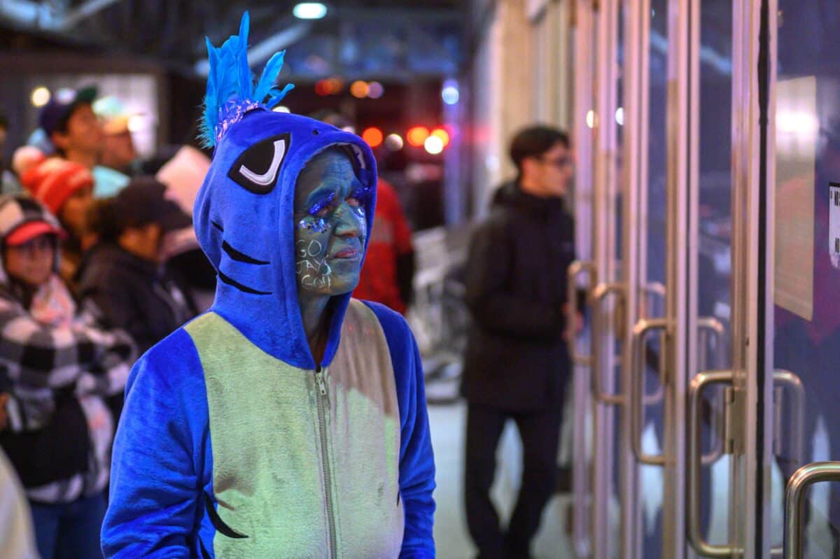 A fan dressed in a Blue Jay costume watches Game Six of the 2025 World Series between the Los Angeles Dodgers and the Toronto Blue Jays on the screen.