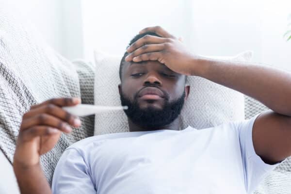 Sick man with fever taking his temperature