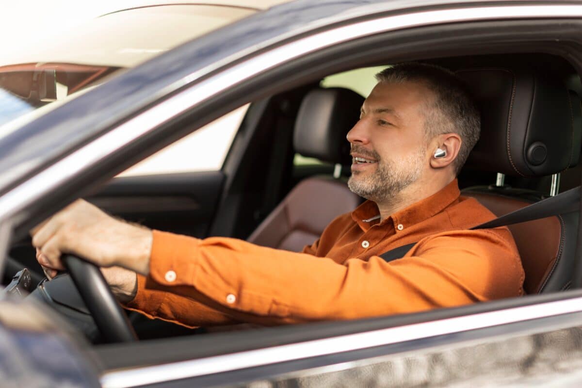 Man using hands-free driving with ear buds for smartphone