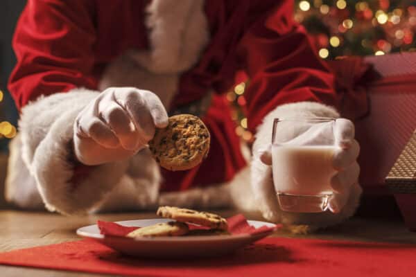 Santa Claus having a delicious cookie with glass of milk
