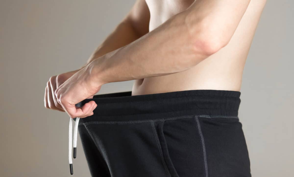 Man pulling open his pants showing weight loss or looking in his pants