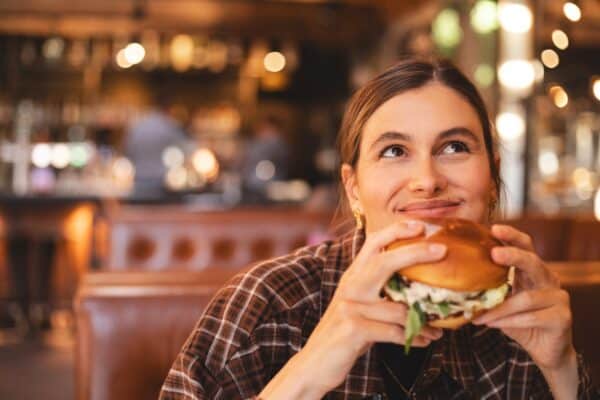 Woman smiling while she eats a delicious hamburger or cheeseburger