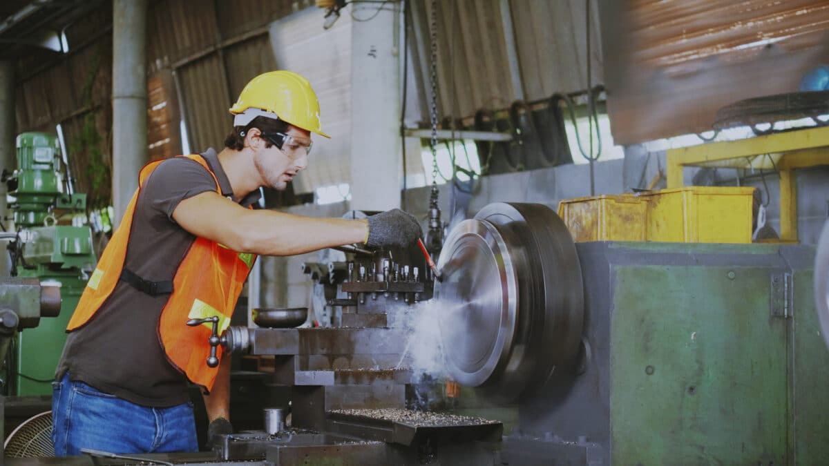 A construction or factory worker grinds steel.