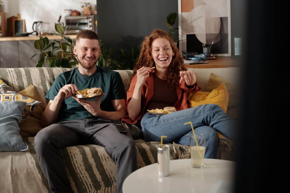 Young,Cheerful,Woman,Pointing,At,Tv,Screen,And,Laughing,While