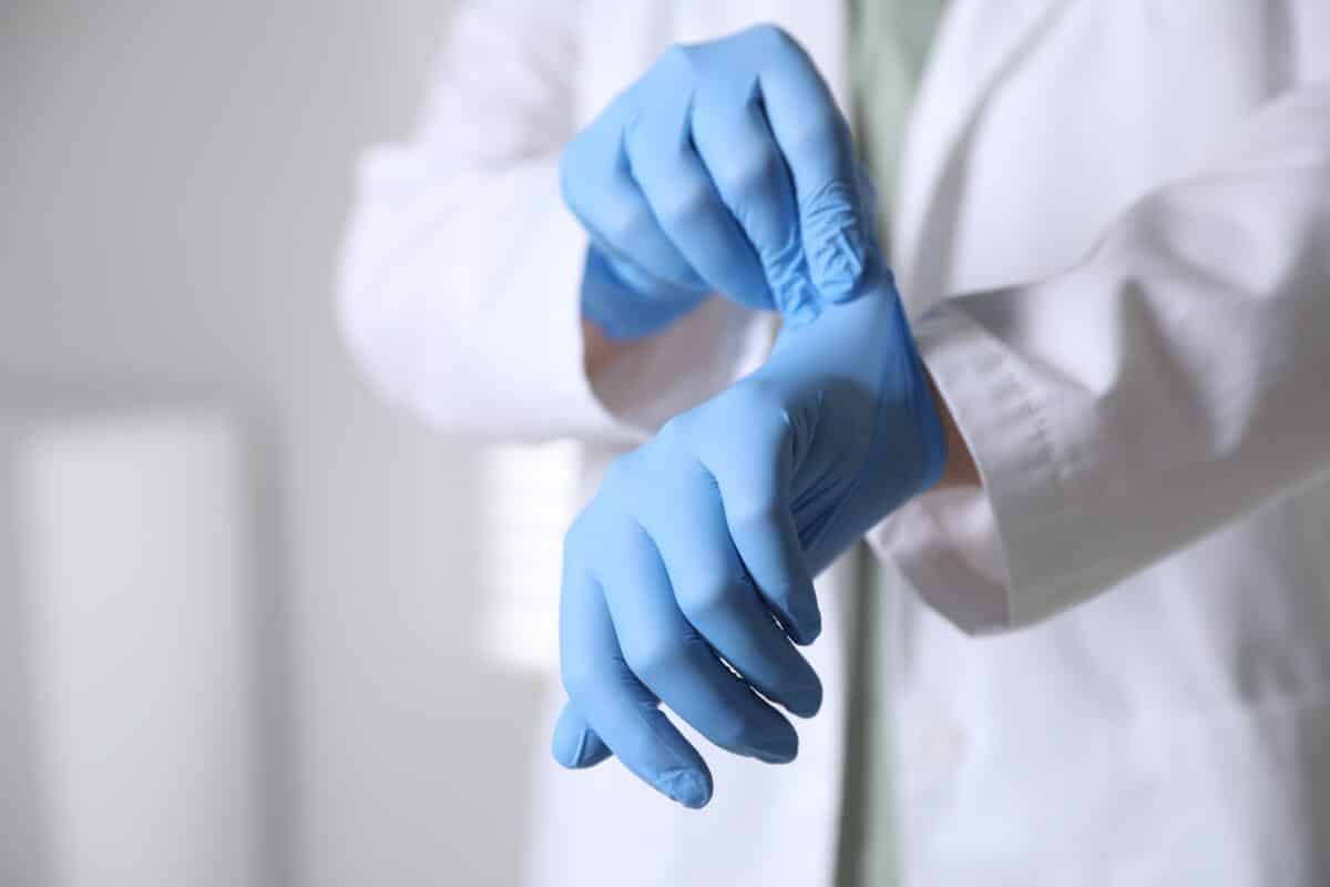 Medical,Worker,Putting,On,Gloves,In,Hospital,,Closeup