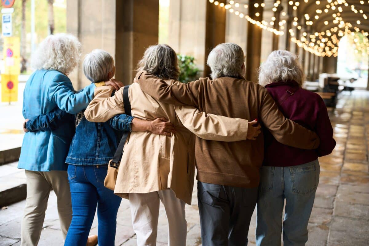 Seniors,Walking,Arm,In,Arm,Through,A,City,Colonnade,,Older