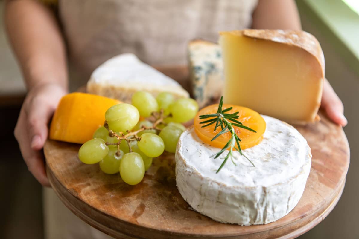 Gourmet artisan cheese platter with fruits.