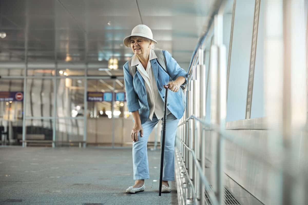 Older woman with cane struggling with knee pain