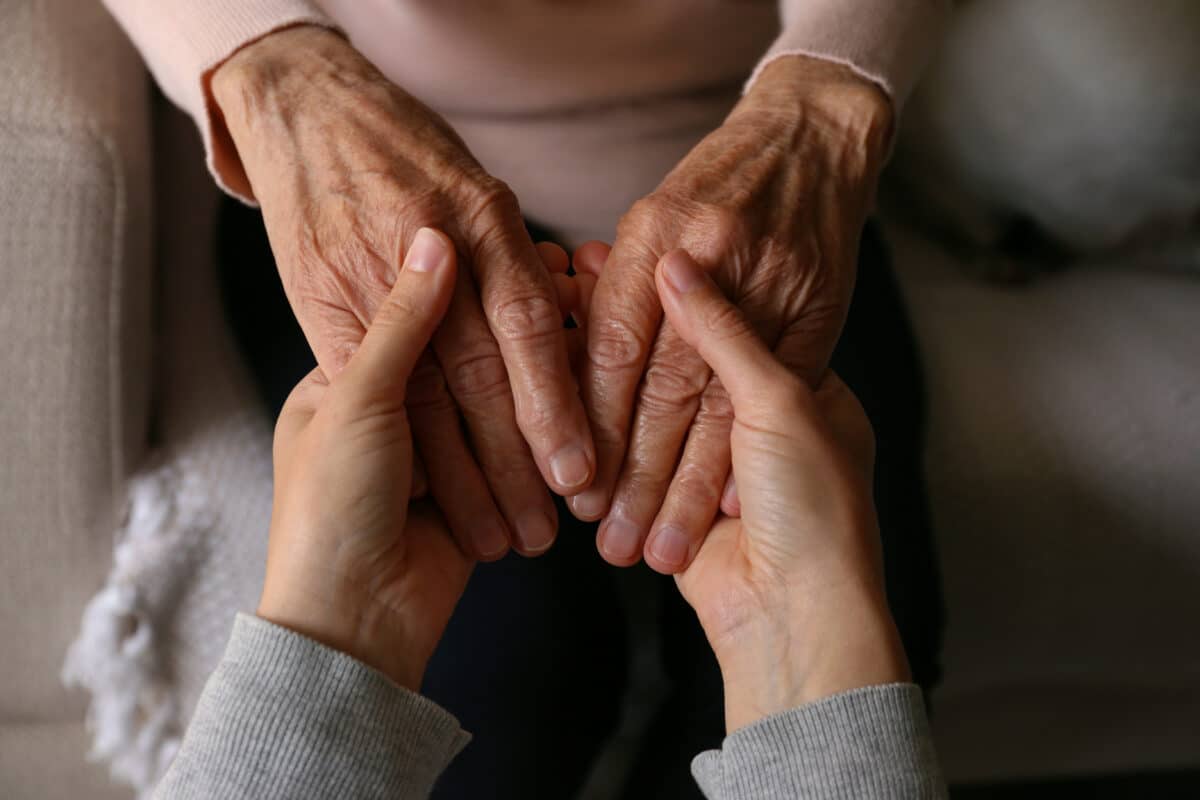 Elderly woman’s hands being held