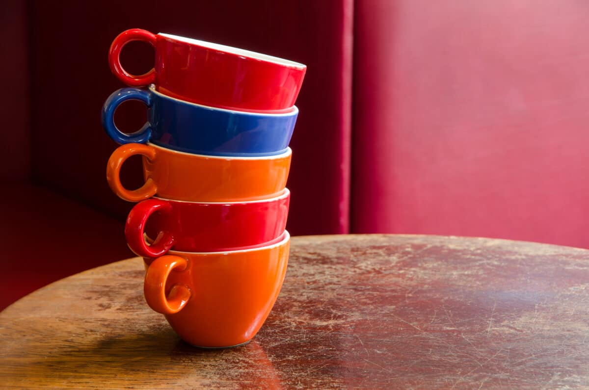 colorful coffee cups stacked on an old wooden table in a cafe