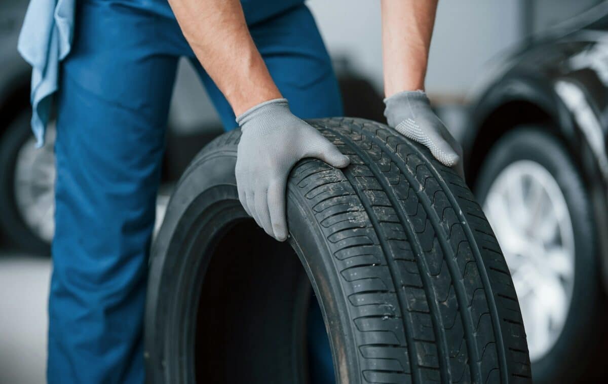 A mechanic holds a rubber car tire