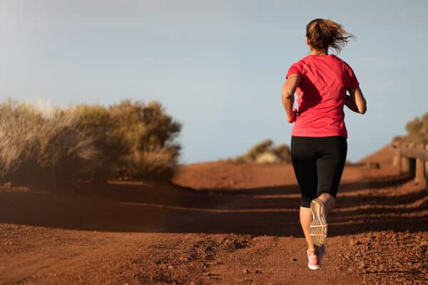 Fitness woman runner athlete running at road, working out cardio on nature landscape