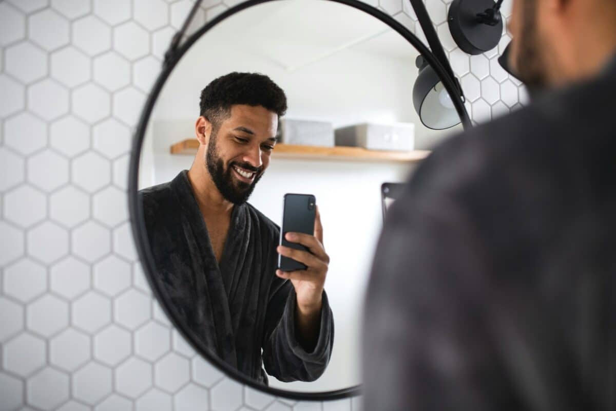 Man taking a selfie of himself in the bathroom mirror