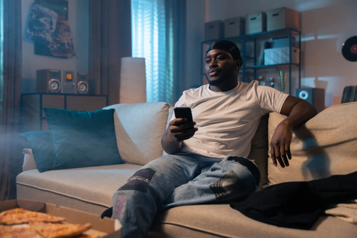 Man watching TV on the couch at night eating pizza
