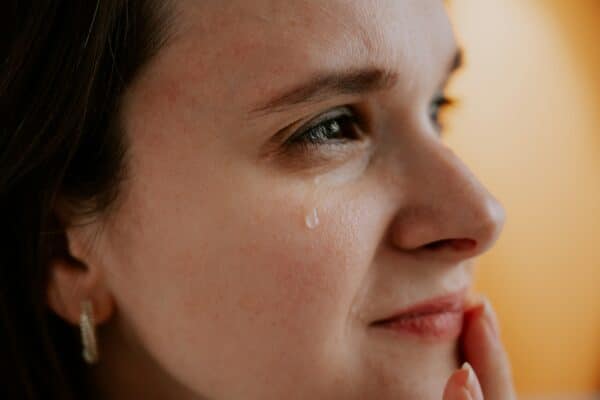 Woman crying, with tear drop on her cheek