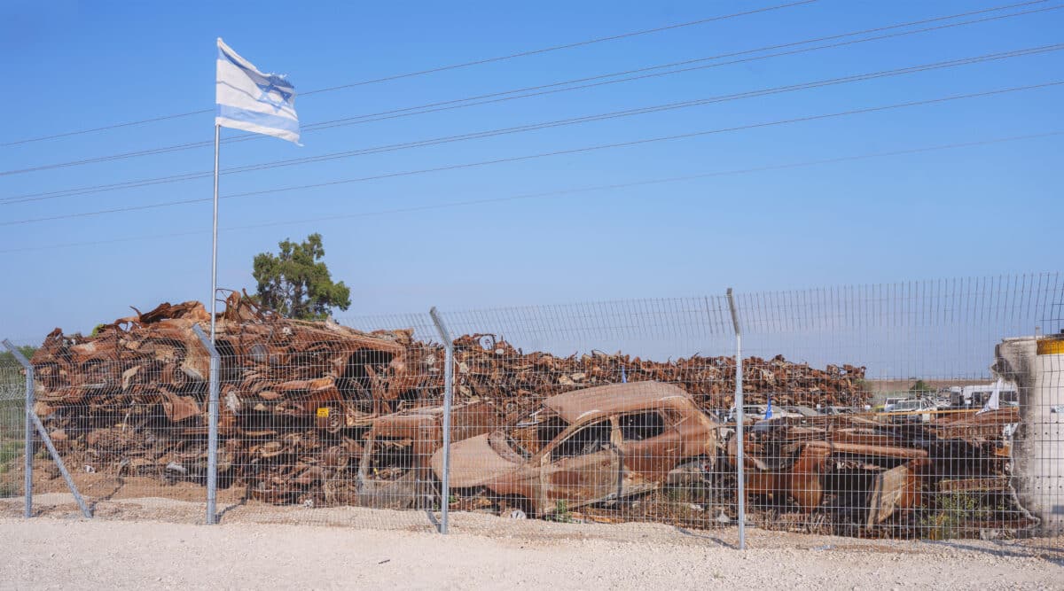 An Israeli flag flies over a small portion of the vehicles that were attacked and burned on 7 October in the Gaza Envelope border area.