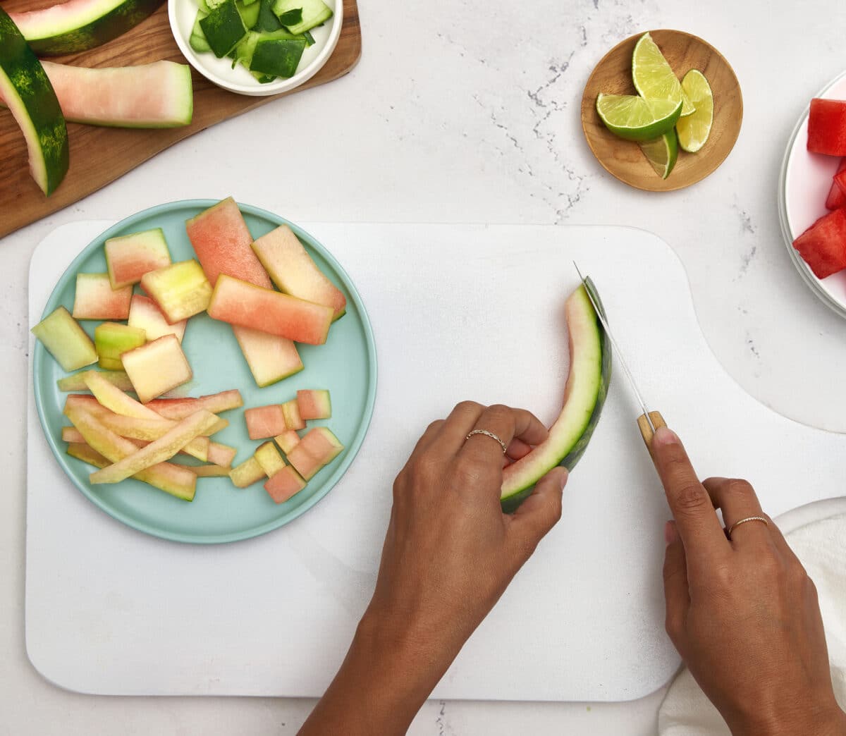 A person cutting the rind from a watermelon slice