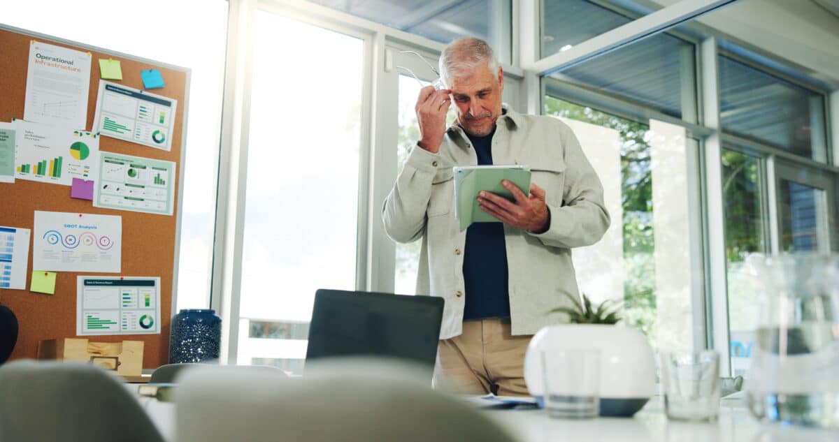 Mature, confused businessman and planning with tablet for company statistics or deadline in office. Low angle, frustrated man or thinking with technology for bad investment or mistake in workplace