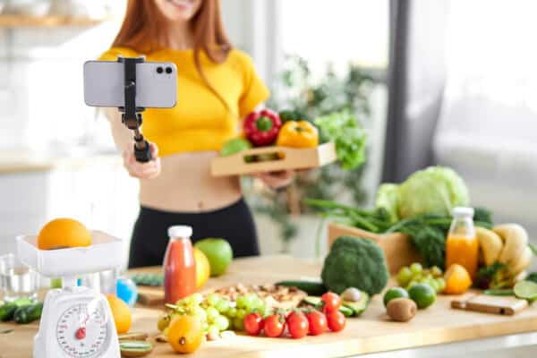 Social media and content creator occupation new job in future. beauty caucasian blogger holding fresh food, going to make homemade salad breakfast and recording video for online channel live