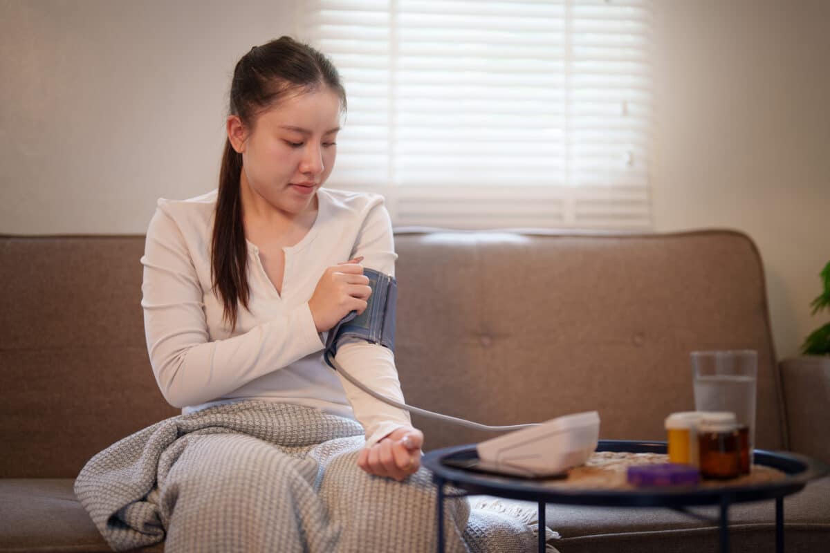 Woman measuring blood pressure with digital monitor at home for healthcare routine