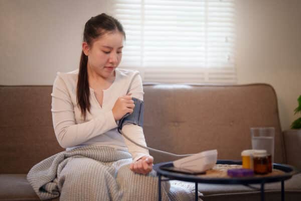 Woman measuring blood pressure with digital monitor at home and medication