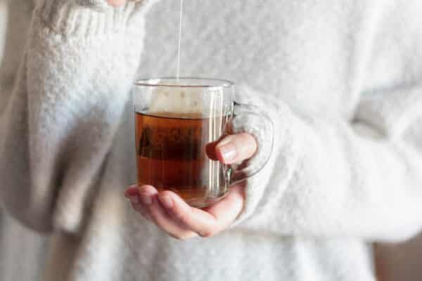 Woman hands dipping tea bag in hot water