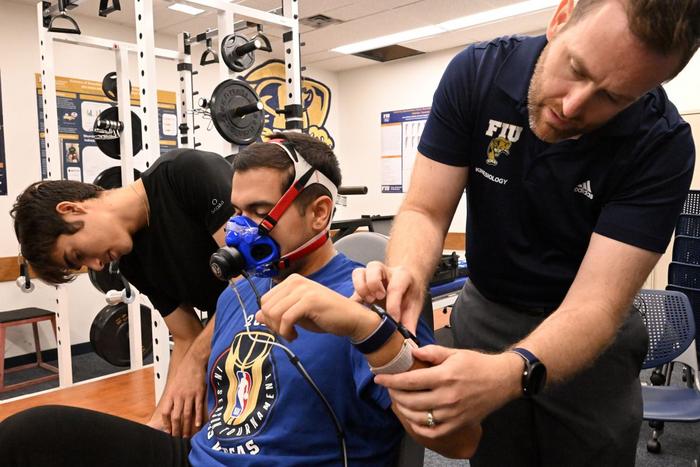 Pic From left, bachelor's student Gabriel Cabeda Ramirez, Ph.D. student Daimien Campos and FIU professor Jason Kostrna review readings from four smartwatches worn by Campos as he rides a stationary bike. Their study evaluated how accurately popular smartwatches estimate calories burned during exercise.