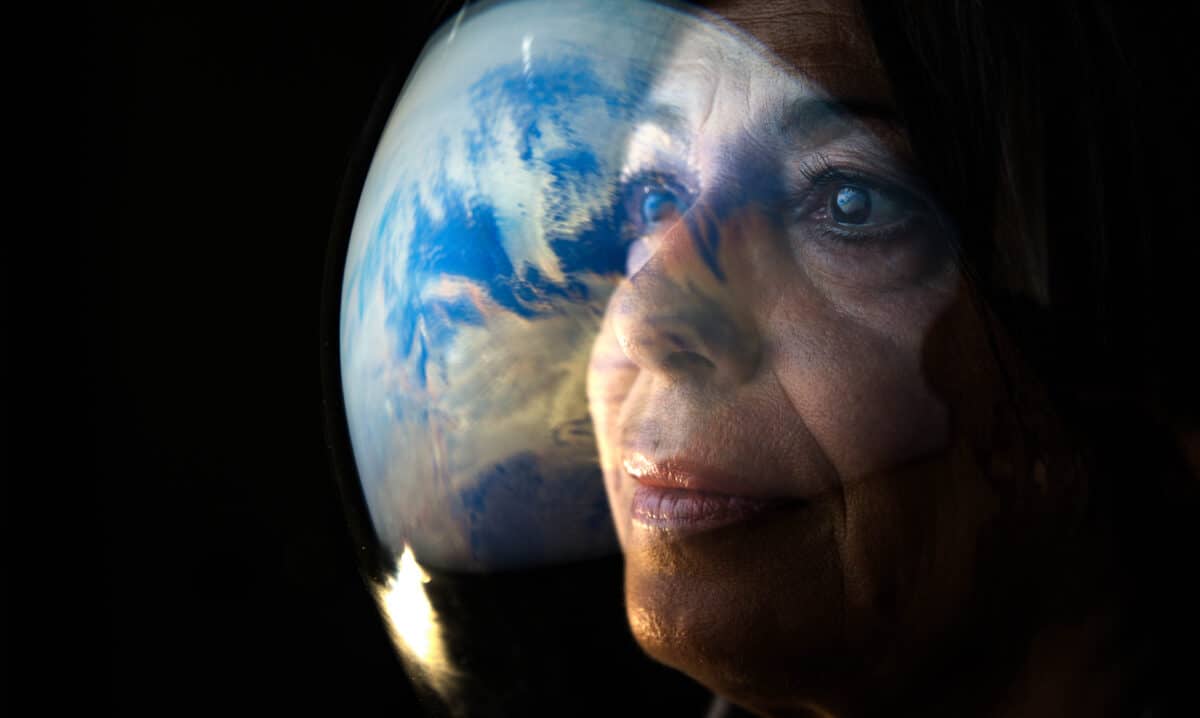 Portrait of the adult female astronaut looking at planet earth – Space travel, exploration and solar system colonization concept.