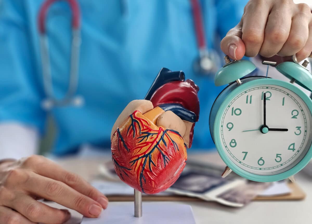 Cardiologist holds alarm clock model of heart in clinic