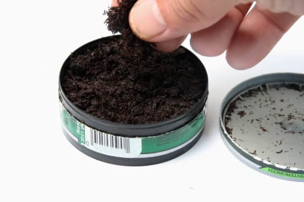 Can of tobacco with a hand getting a pinch for use