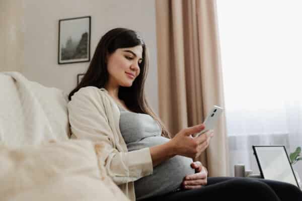 Pregnant woman on the couch using her smartphone