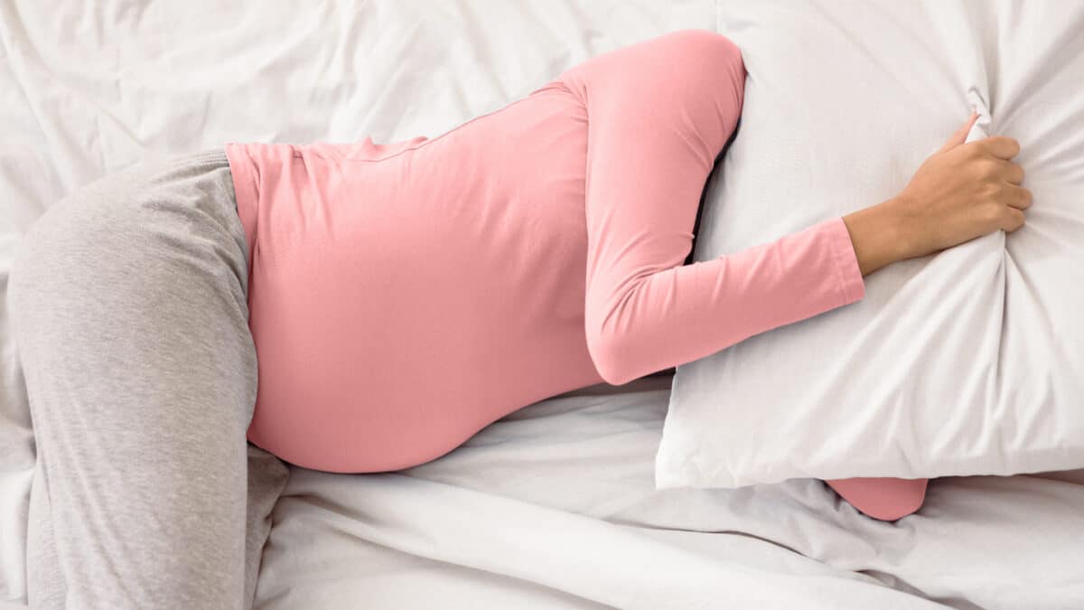 Pregant lady sleeping and covering head with pillow