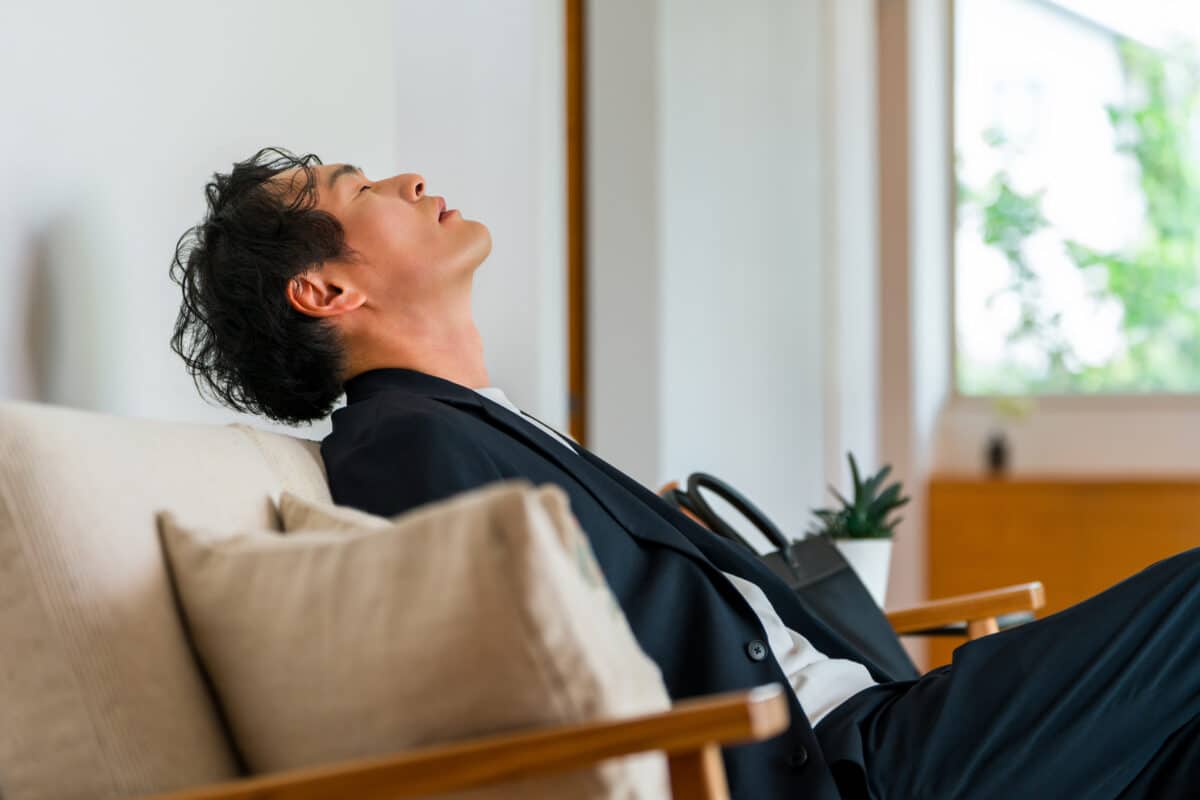 Tired Businessman Resting on a Sofa After Work, Struggling with Stress and Fatigue